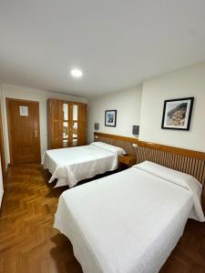 a hotel room with two beds with white sheets at Pensión Mencia in Lugones