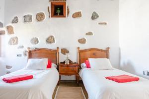 two beds in a room with rocks on the wall at Casa Emblemática Garaday Lanzarote. in Tinajo