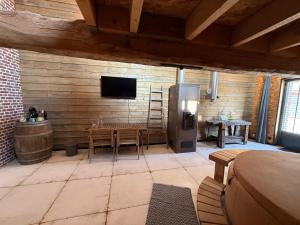 a kitchen with a table and a television in a room at Odyssée - Chambre d'hôtes avec sauna privatifs, spa et filet suspendu in Zeggers-Cappel
