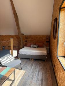 a room with two beds and a chair in it at Odyssée - Chambre d'hôtes avec sauna privatifs, spa et filet suspendu in Zeggers-Cappel