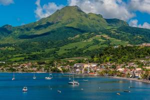 a group of boats in a body of water with a mountain at Studio Colibri vue mer in Quartier Morne Acajou