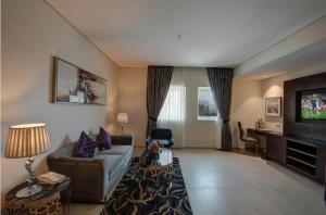a living room with a couch and a tv at Hotel The De - Pacific Suites Near Delhi IGI Airport in New Delhi