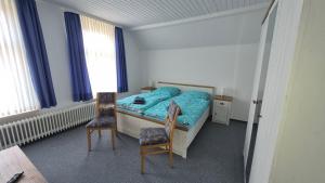 a small bedroom with a bed and two chairs at Goode Wind in Norden +4 photos