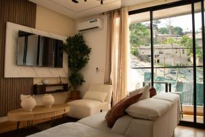 a living room with a couch and chairs and a large window at Residence Hôtel le Danoré Bastos in Yaoundé