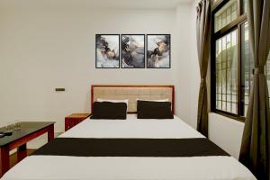 a bedroom with a bed with three paintings on the wall at SPOT ON Golden Eagle Residency in Barpeta