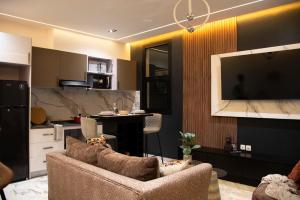 a living room with a couch and a tv and a kitchen at Residence Hôtel le Danoré Bastos in Yaoundé