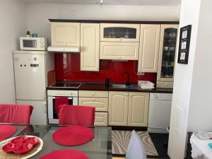 a kitchen with white cabinets and a red wall at Una Mirage in Bihać