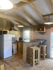 a kitchen with a white refrigerator and wooden cabinets at Camping Familial Buffalo Hacienda in La Seyne-sur-Mer