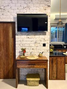 a kitchen with a table with a tv on a brick wall at King Simba Apartment Hotel & Restaurant in Bwejuu