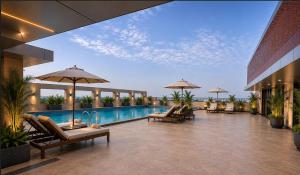 a resort with a swimming pool with chairs and umbrellas at The Crown Puducherry in Pondicherry