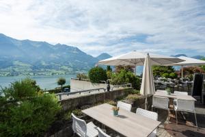 a patio with an umbrella and tables and chairs at Seehotel Wilerbad Spa & Seminar in Sarnen
