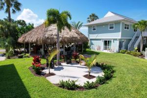 a house with a grass umbrella and palm trees at The Dex at Coconut Cove in Fort Myers Beach
