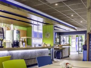 a restaurant with green walls and tables and chairs at ibis Budget Colmar Centre Gare in Colmar