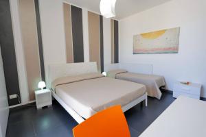 a bedroom with two beds and an orange chair at Le Murge Del Salento Hotel b&b Depandance in Uggiano la Chiesa