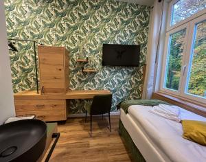 a bedroom with a bed and a desk with a television at Gasthof Schloss Hubertus in Erfurt