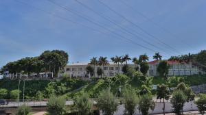 a large white building with palm trees and a road at Hà Tiên Hạnh Phúc Hotel in Hà Tiên