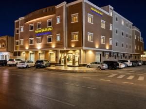 a large building with cars parked in a parking lot at توارن للشقق المخدومة - الاقتصادية in Riyadh