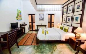 a bedroom with a bed and a desk and a television at Sunday Rainforest Chiangmai Hotel in Chiang Mai