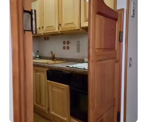 a kitchen with wooden cabinets and a black appliance at Appartamento Sestriere in Sestriere
