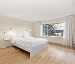 a white bedroom with a white bed and a window at Vancouver sea view Palace inn in West Vancouver