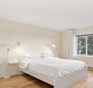 a white bedroom with a white bed and a window at Vancouver sea view Palace inn in West Vancouver