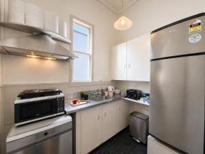 a kitchen with white cabinets and a stainless steel refrigerator at CitiRooms Auckland in Auckland