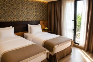 two beds in a hotel room with a window at Hotel Gareji Kakheti in Sagarejo