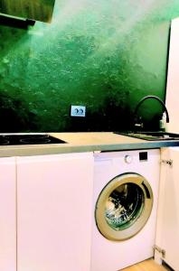 a washing machine in a kitchen with a green wall at Muna Living in Riga