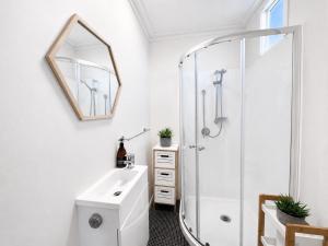 a bathroom with a shower and a sink and a mirror at CitiRooms Auckland in Auckland
