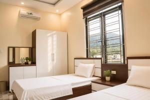 two beds in a room with a window at Cat Ba Sky Home in Cat Ba