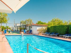 a large swimming pool with blue chairs and a house at Hotel Central Wellness in Sorrento