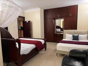 a bedroom with two beds and a chair in it at Lakepoint Villa in Entebbe