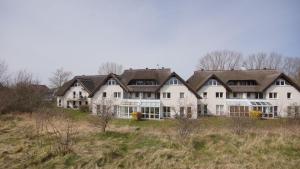 a large white house on a hill in a field at Strandhaus Lobbe, App 04 - Bade- & Saunawelt täglich inklusive in Lobbe