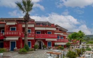 a red building with a palm tree in front of it at Achilleas Hotel in Parga +34 photos