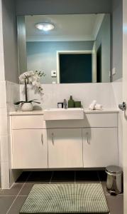 a bathroom with a white sink and a mirror at The Snug Suite in Cooranbong