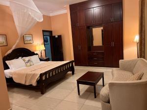 a bedroom with a bed and a couch and a chair at Lakepoint Villa in Entebbe