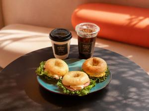 a plate with a donut sandwich and a cup of coffee at Prince Smart Inn Naha in Naha