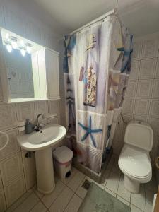 a bathroom with a sink and a toilet and a shower curtain at Irene's Sunny residence in Limnos in Néa Koútali
