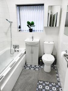 a bathroom with a toilet and a tub and a sink at B&G Homes in Hollinwood