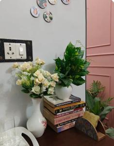a table with a stack of books and a vase with flowers at Whispring hills hotel in Sodākor