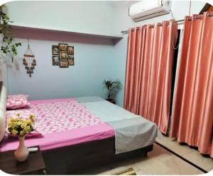 a bedroom with a pink bed and orange curtains at Whispring hills hotel in Sodākor