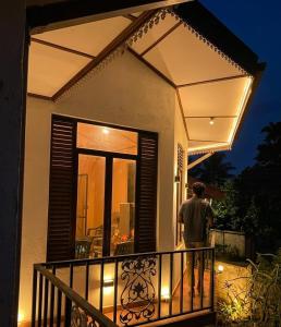 a man standing on the balcony of a house at night at Freedom Rest Rooms in Anuradhapura