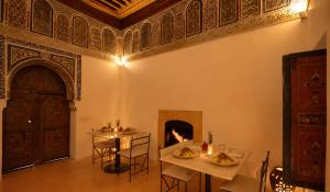 a dining room with a fireplace and a table and chairs at Hotel & Spa Dar Baraka & Karam in Marrakesh
