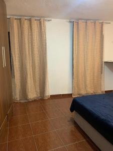 a bedroom with a bed and two windows with curtains at Sobiuai 72 in Ouro Preto