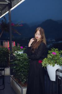 a woman in a black dress standing on a balcony at Thái house Mộc Châu in Bản Chiềng Di