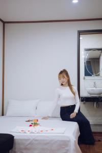 a woman sitting on a bed in a room at Thái house Mộc Châu in Bản Chiềng Di