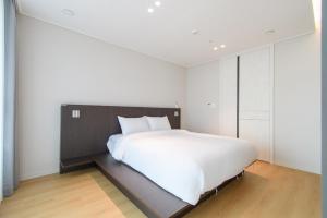 a bedroom with a large white bed and white walls at 플럼바고올스위트402 in Chosan-ni