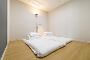 a white room with a bed with white sheets at 플럼바고올스위트402 in Chosan-ni