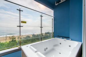 a bath tub in a bathroom with a large window at 플럼바고올스위트402 in Chosan-ni