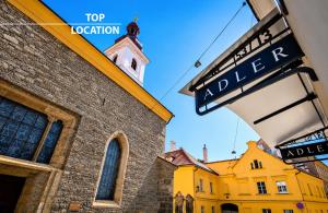 a yellow building with a clock tower and a street sign at Hotel Adler - Czech Leading Hotels in Prague